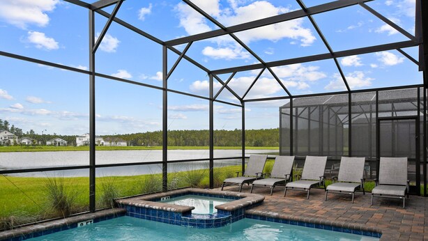 An indoor pool area with a view of a road and greenery, surrounded by a metal frame structure. - Last Minute Disney! Private Pool, Hot Tub, Game Room & Themed Bedrooms. Book Now! #38250 (Orlando)