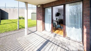 A covered patio with a brick wall, sliding glass doors leading to an indoor seating area with a table and chairs. - Chic 2Bed W/Canal Views, 15 Min to Kilmainham Gaol (Kilmainham)
