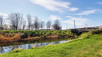 A stone bridge over a calm river, surrounded by lush greenery and leafless trees.