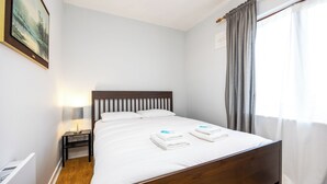 A neatly made bed with white linens and two folded towels, a bedside lamp, and a framed picture on the wall. - Chic 2Bed W/Canal Views, 15 Min to Kilmainham Gaol (Kilmainham)