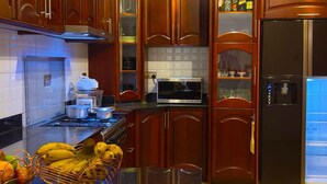 Una cocina con armarios de madera, un refrigerador de acero inoxidable, un microondas y una cesta de frutas en la encimera.