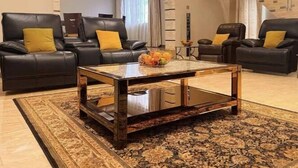 Una sala de estar moderna con dos sofás de cuero negro, una mesa de centro de vidrio y una alfombra estampada.