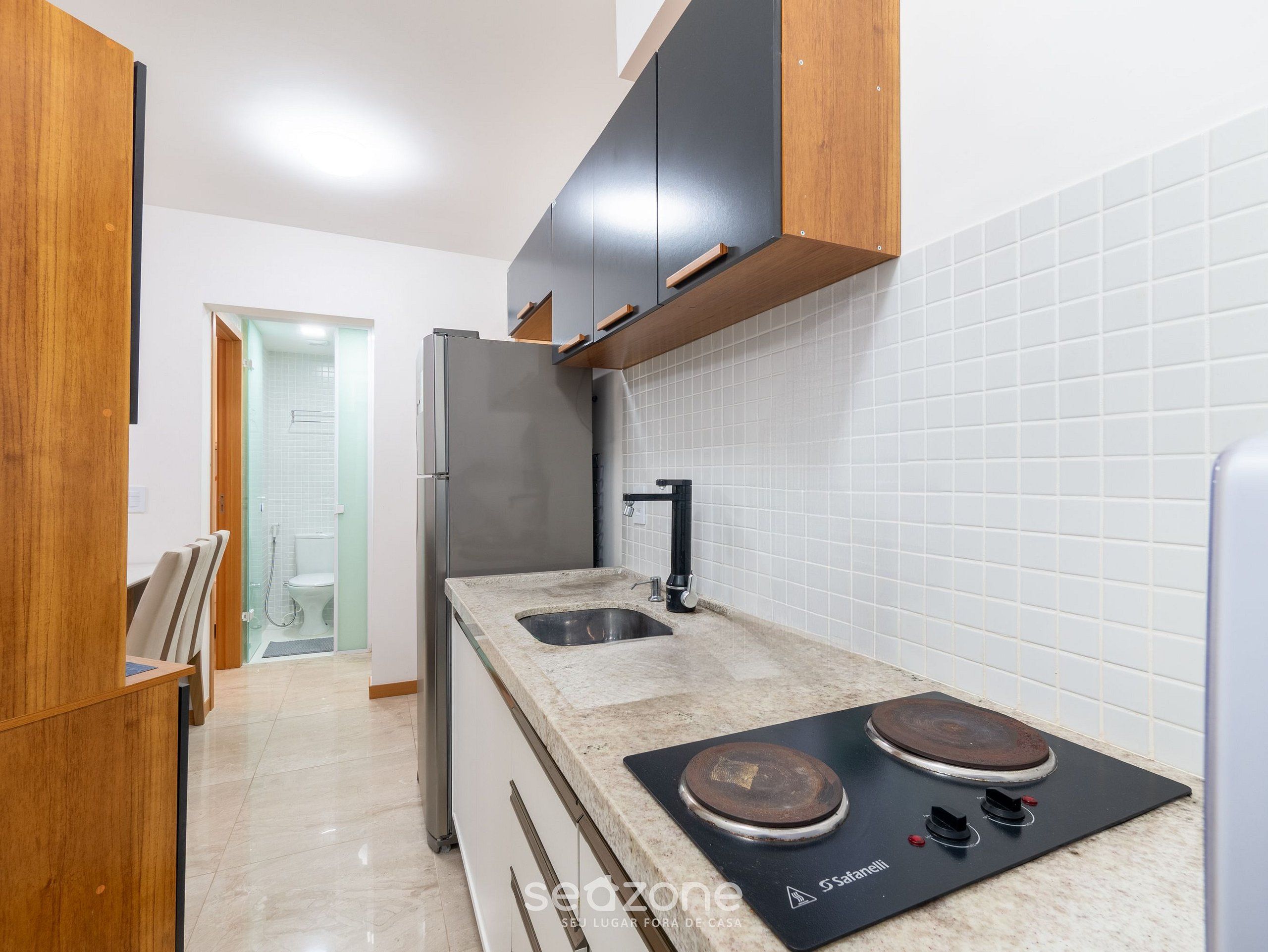 Una cucina moderna con frigorifero in acciaio inossidabile, un lavello a due vasche e piano cottura integrato.