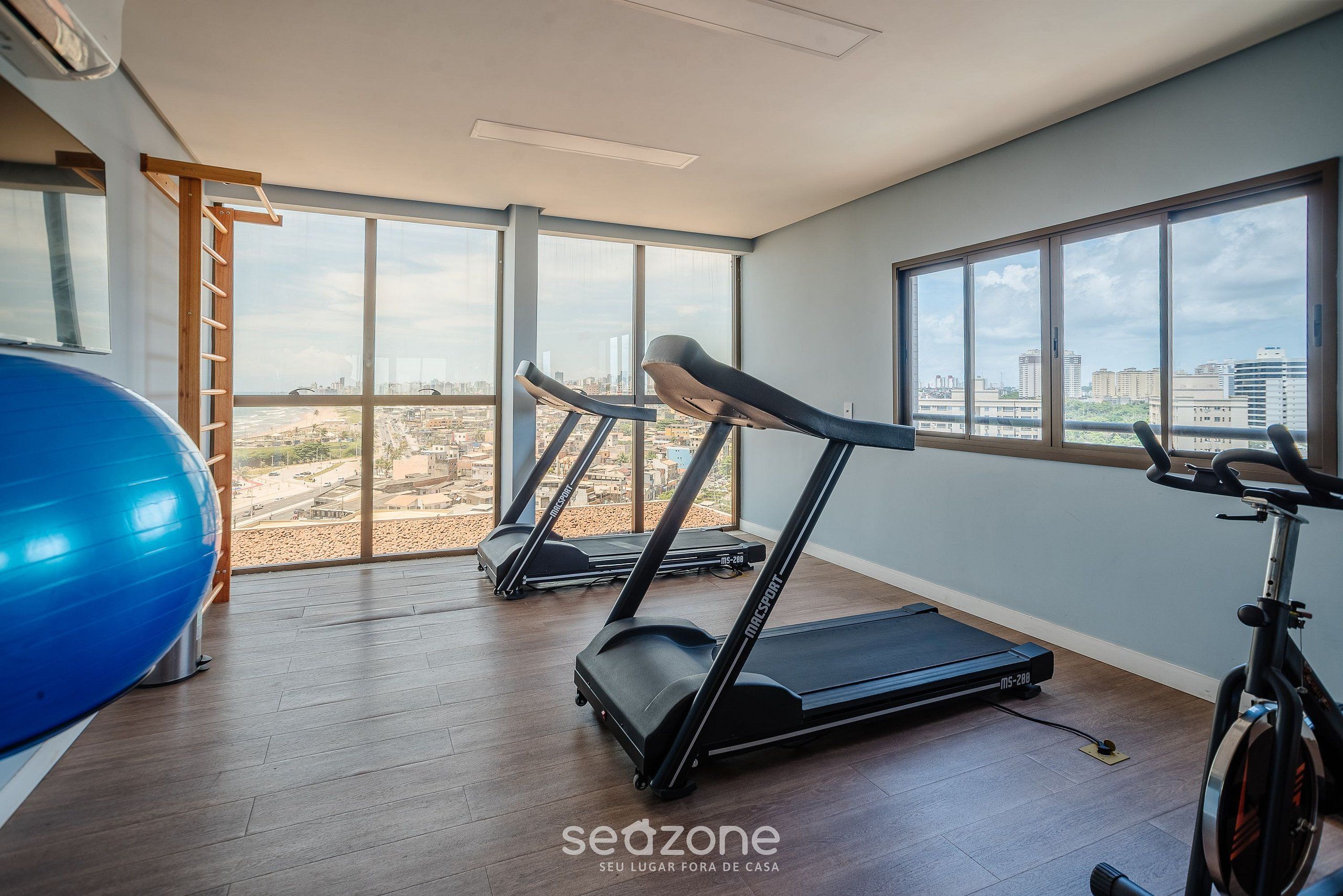 A gym with treadmills, a stationary bike, and a blue exercise ball.