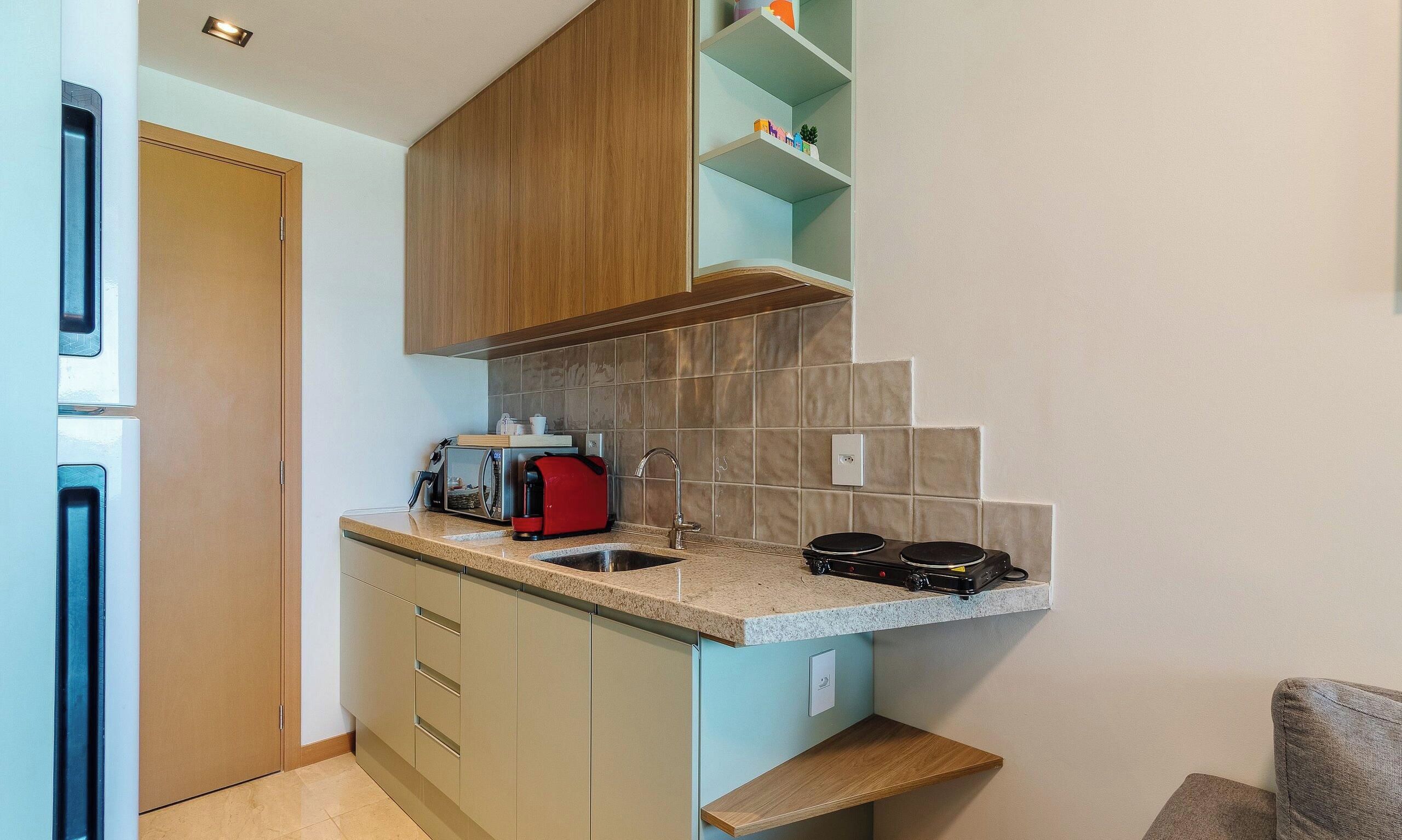 Una cucina compatta con forno a microonde, macchina del caffè e piano cottura a gas portatile.