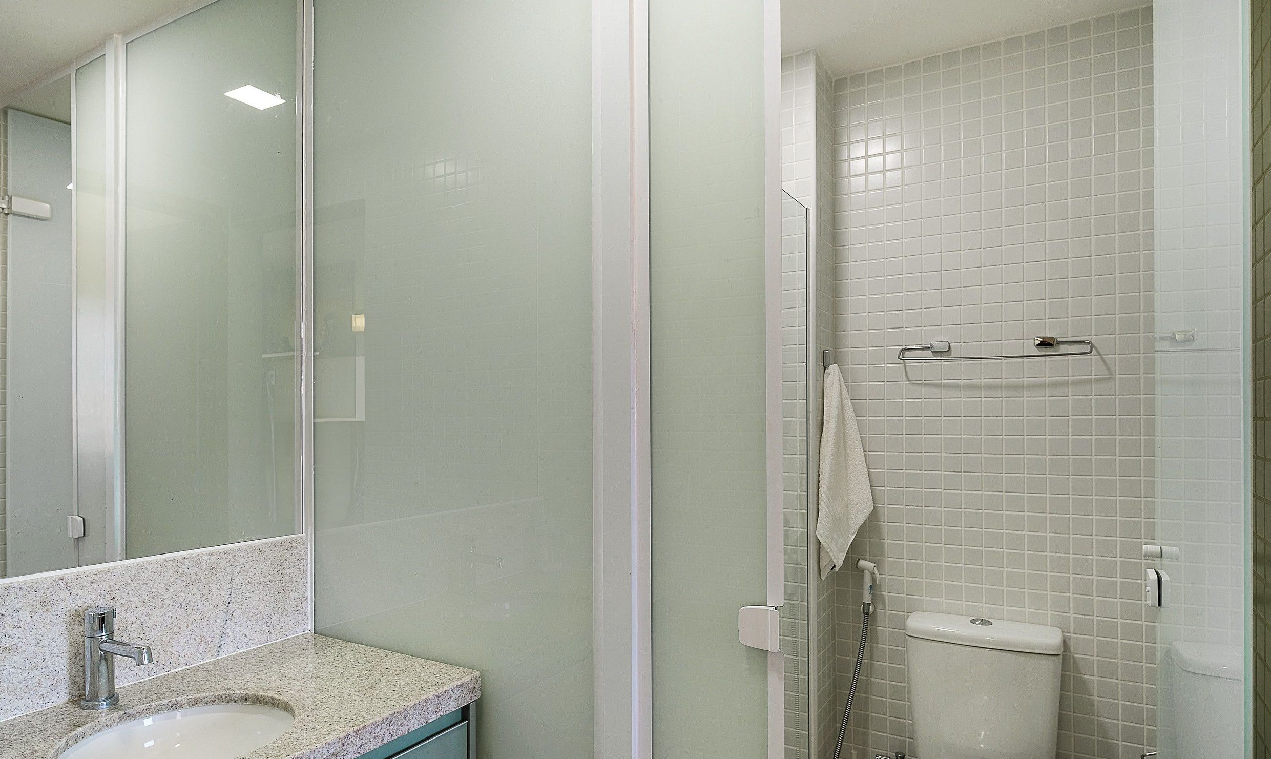 Une salle de bain avec une douche à parois de verre, des toilettes blanches et un comptoir en granit avec un lavabo.