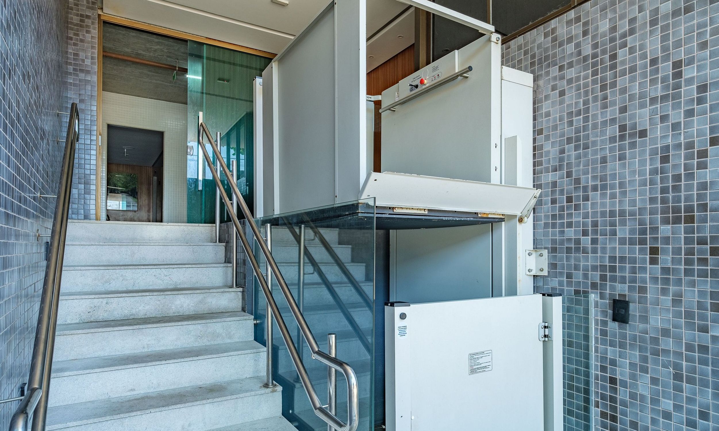 A staircase with metal railings leading to a landing with a glass door.
