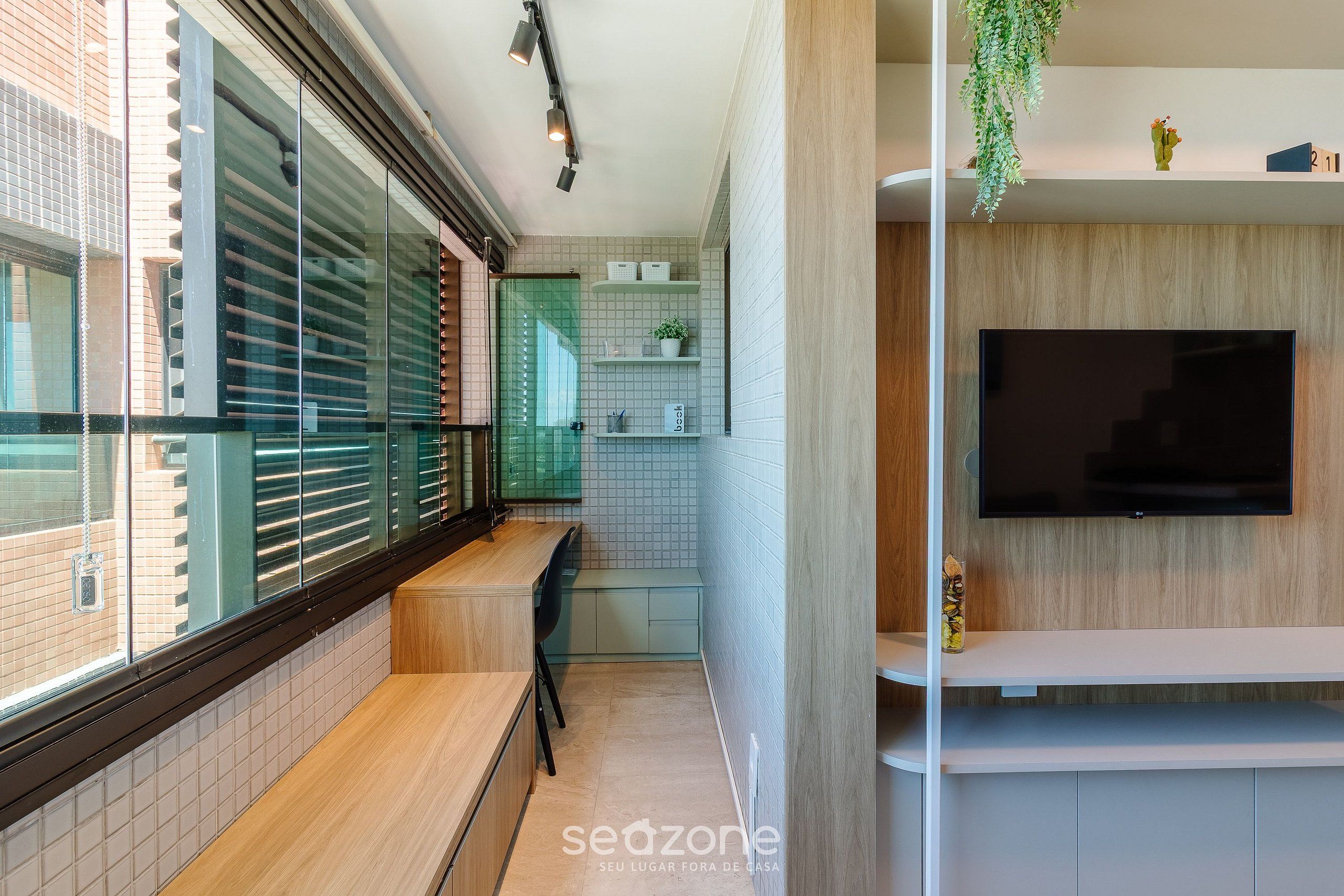 Una cocina moderna con televisor integrado, una ventana con persianas y una pequeña planta en el estante.