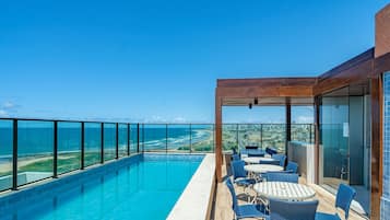A rooftop pool with a clear view of the ocean and city skyline.