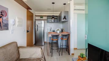 Un espacio habitable compacto con kitchenette, un sofá y un televisor.
