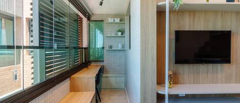 Una cocina moderna con televisor integrado, una ventana con persianas y una pequeña planta en el estante.