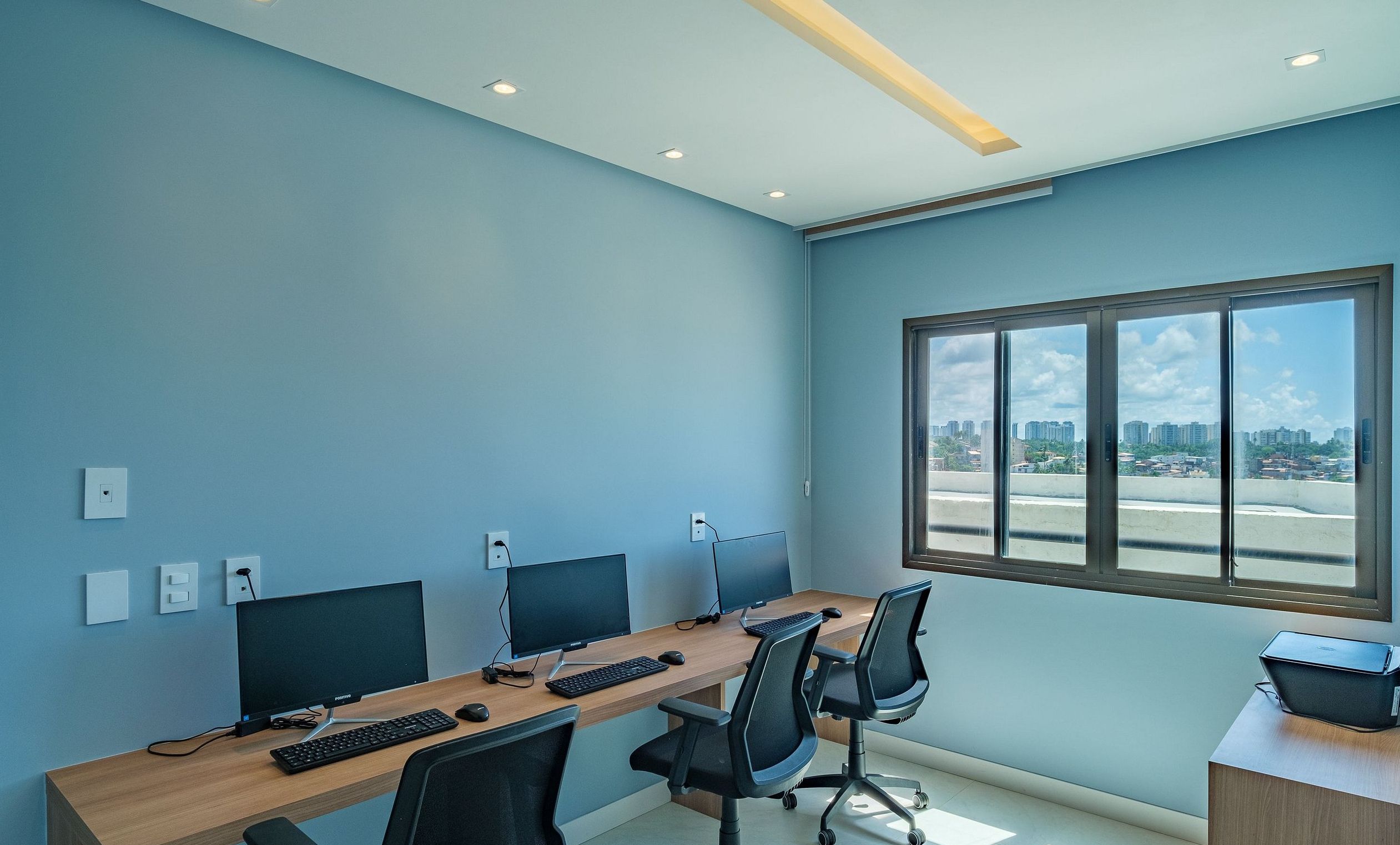 A conference room with a long table, two monitors, a keyboard, and chairs.