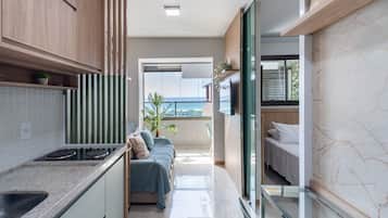 A modern kitchen with a built-in stove, a dining area with a glass partition, and a balcony with a view.
