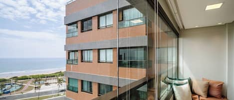 A modern building with multiple floors, large windows, and a view of the ocean.