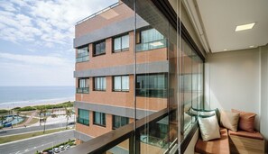 A modern building with multiple floors, large windows, and a view of the ocean.
