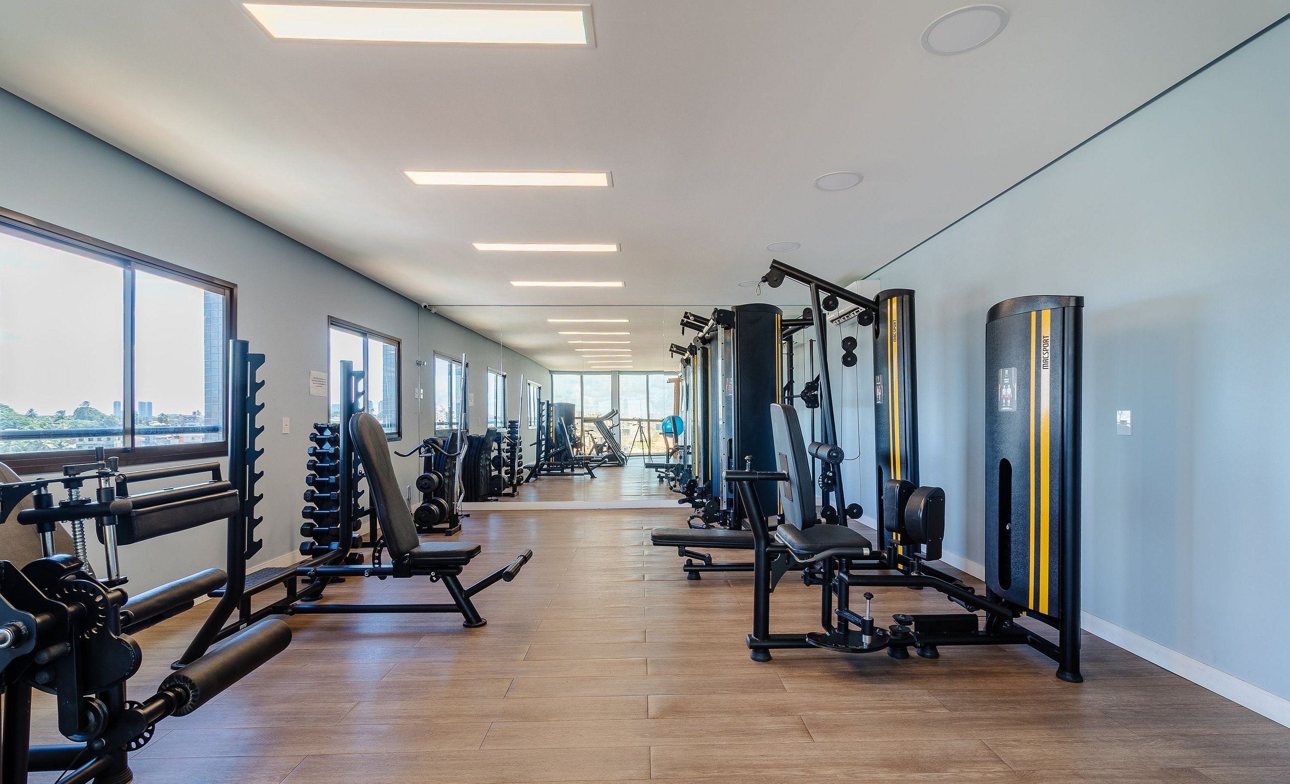 A gym with various exercise equipment, large windows, and a view of the city.