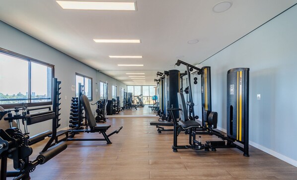 A gym with various exercise equipment, large windows, and a view of the city.