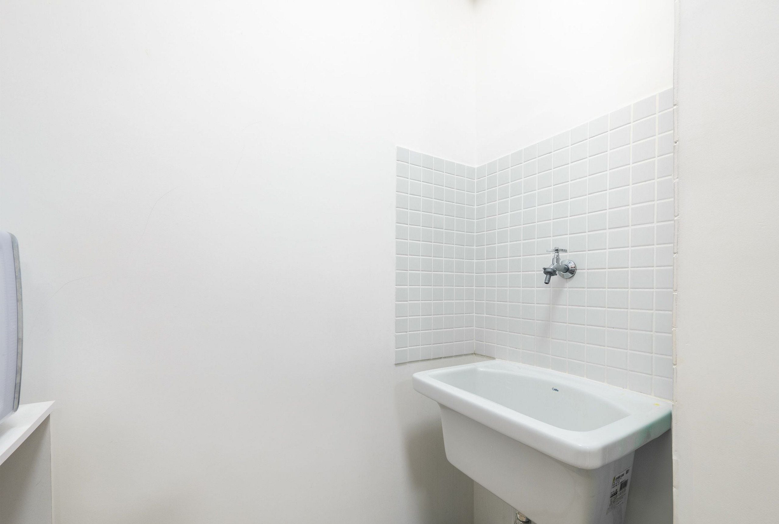 A bathroom with white tiles, a white sink, and a white toilet.