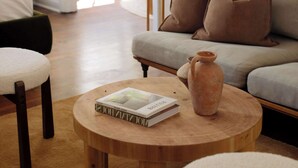 Ein gemütliches Wohnzimmer mit einem Holztisch, einer braunen Couch und einem grünen Sessel.