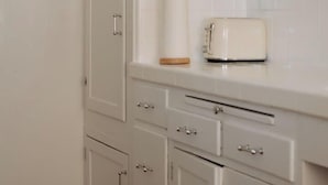 Eine Küche mit weißen Schränken, einem Toaster und einer weißen Arbeitsplatte.