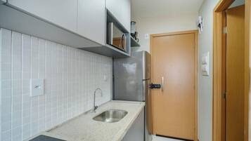 Una cocina compacta con un lavamanos de acero inoxidable, horno empotrado y una puerta de madera.