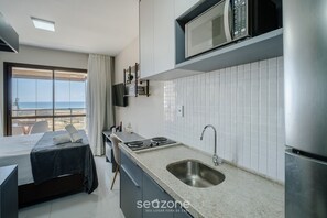 A modern hotel room with a bed, kitchenette, and a view of the sea. - SMT - Building 750m From the Beach in Salvador (Salvador)