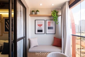 A balcony with a bed, a hanging plant, and framed artwork. - SMT - Building 750m From the Beach in Salvador (Salvador)