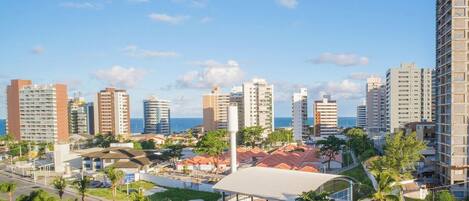 A coastal cityscape with high-rise buildings, a sports complex, and palm trees.
