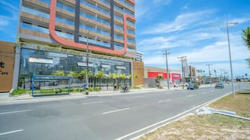 A modern building with a large, curved sign, a covered bus stop, and a clear sky.