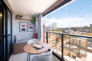 A balcony with a round table, seating, and framed artwork. - SMT - Building 750m From the Beach in Salvador (Salvador)