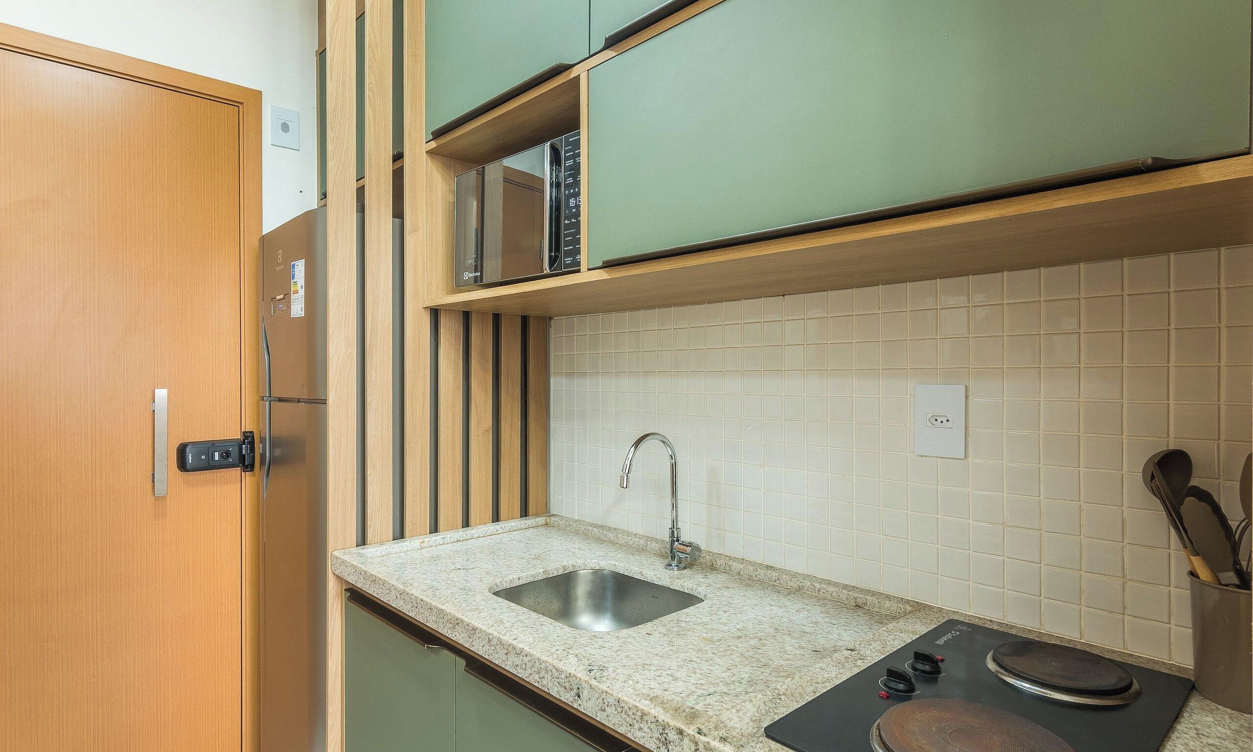 A compact kitchen with a built-in microwave, a sink with a faucet, and a stove with controls.