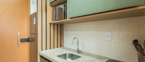 A compact kitchen with a built-in microwave, a sink with a faucet, and a stove with controls.