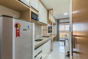 A compact kitchen with a refrigerator, microwave, and sink. - SMT - Building 750m From the Beach in Salvador (Salvador)
