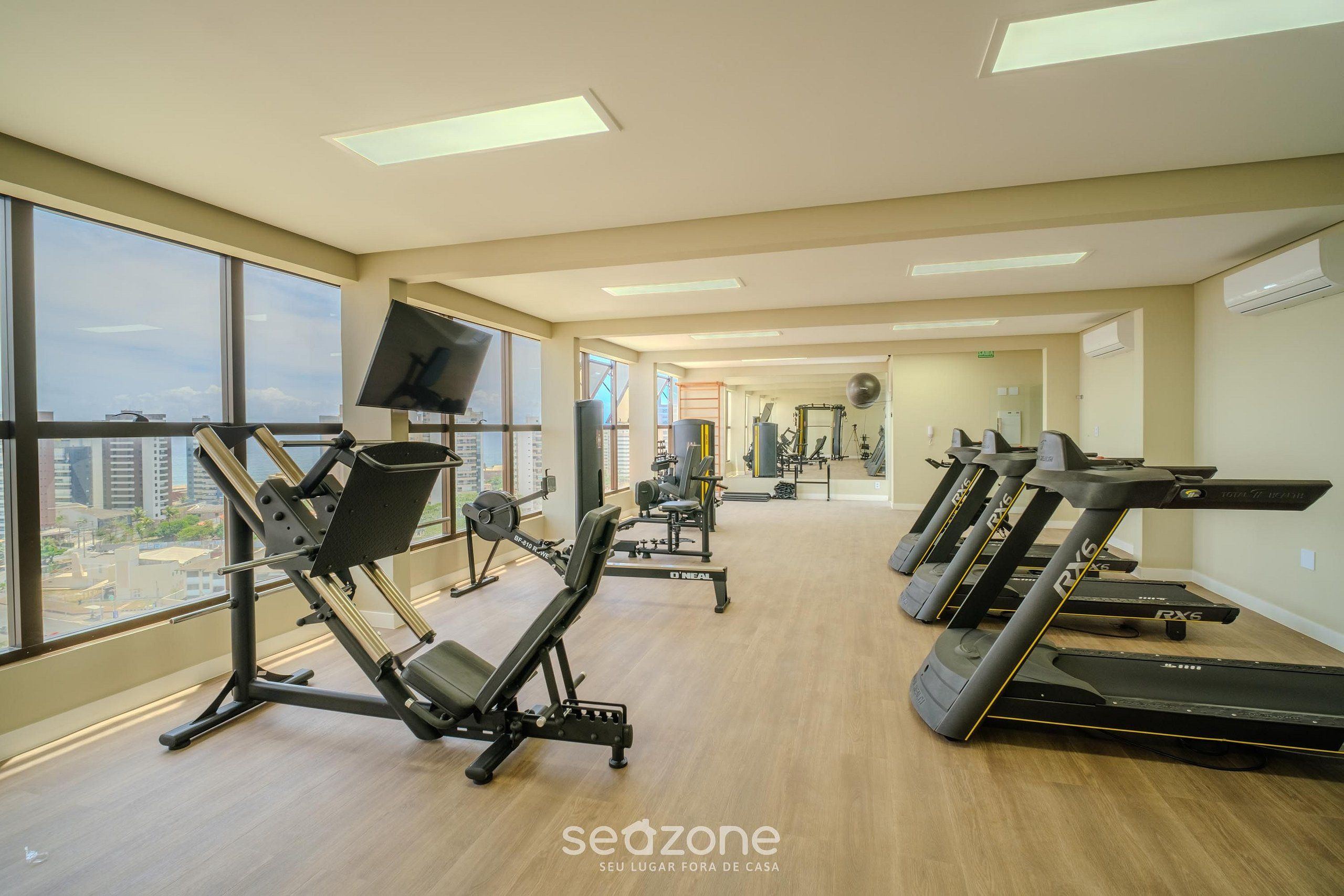 A gym with treadmills, weight machines, and a TV screen.