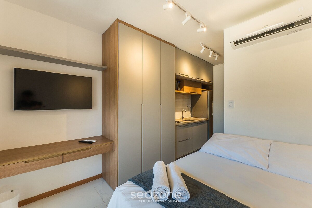 Une chambre moderne équipée d’un lit, d’une télévision, d’une armoire et d’un petit coin cuisine.