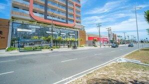 Ένα σύγχρονο κτίριο με μια μεγάλη, καμπυλωτή επιγραφή, μια σκεπαστή στάση λεωφορείου και έναν καθαρό ουρανό.