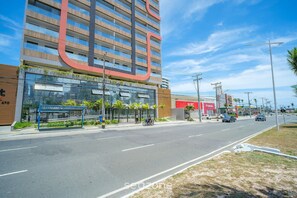 Un bâtiment moderne, doté d’une grande enseigne incurvée, d’un abri-bus et d’un ciel dégagé.