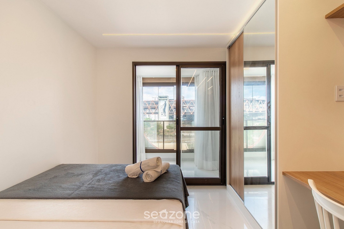 Une chambre moderne avec un lit, une vue à travers une porte coulissante et un bureau en bois.