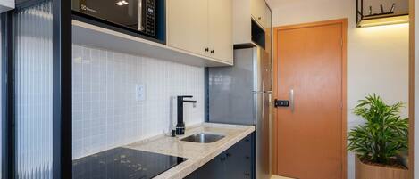 A modern kitchen with a built-in microwave, stainless steel sink, and a wooden door.