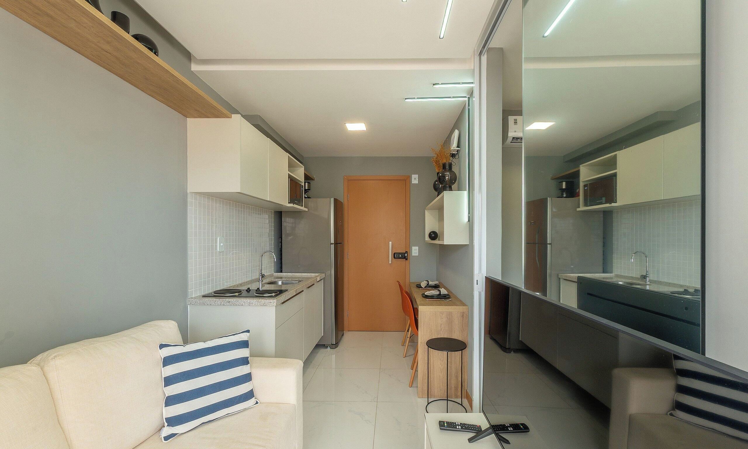 Een compacte keuken met een eethoek, een bank met gestreepte kussens, en een deur naar een andere kamer.