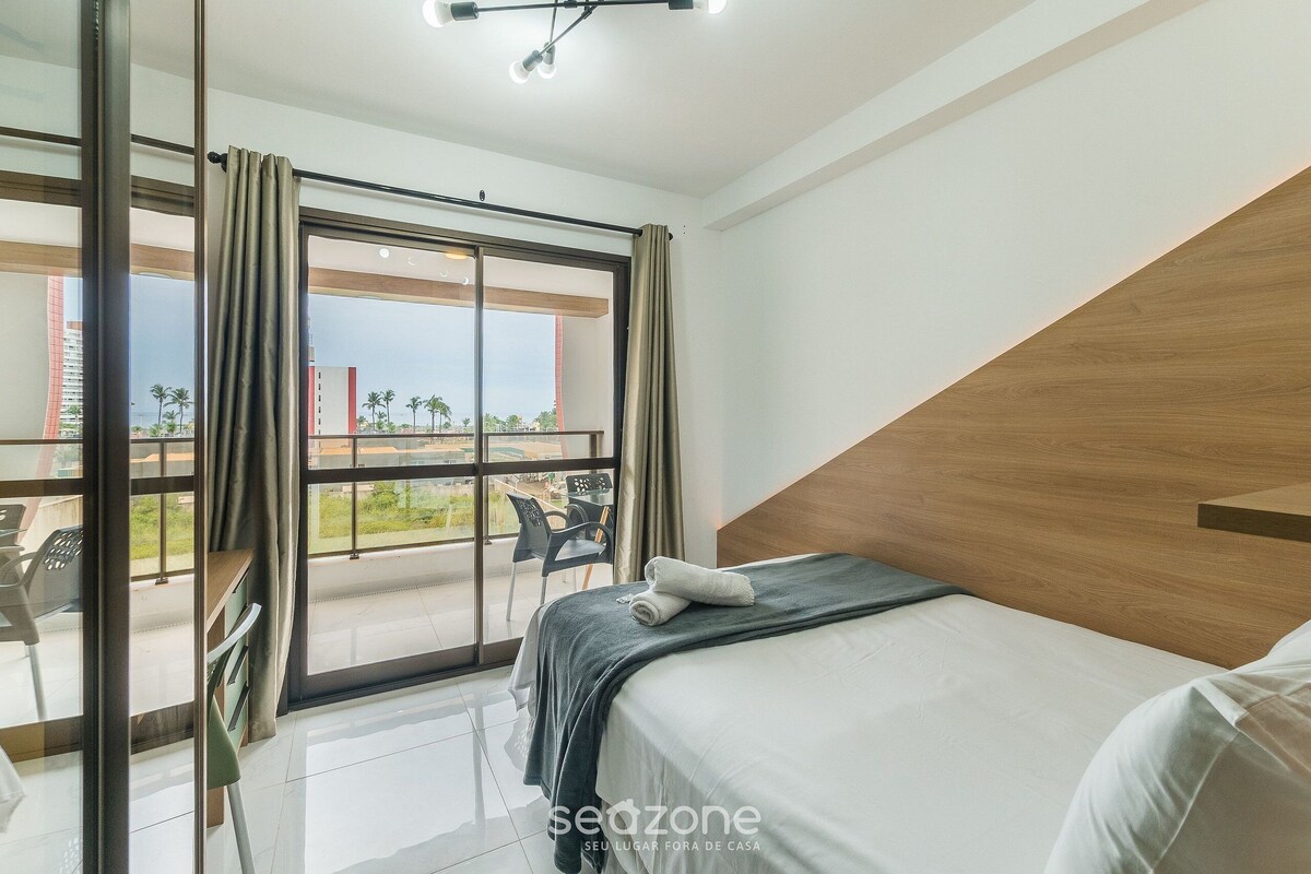 Une chambre d’hôtel avec un lit, une vue sur l’extérieur et un balcon équipé de chaises.
