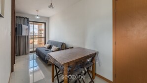 Ein Zimmer mit Holztisch, Stühlen, einer Couch, einer Schiebeglastür und einer Holztür.