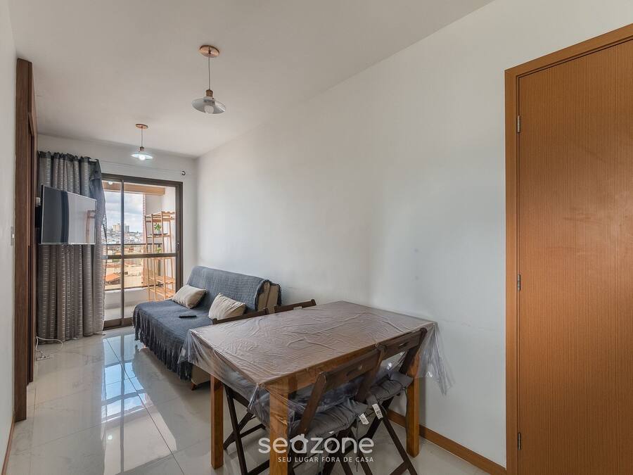 A room with a wooden table, chairs, a sofa, a sliding glass door, and a wooden door.