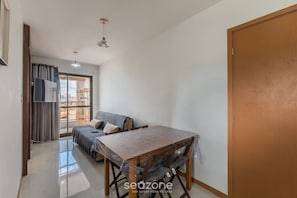 A room with a wooden table, chairs, a sofa, a sliding glass door, and a wooden door. - SMT - Building 750m From the Beach in Salvador (Salvador)