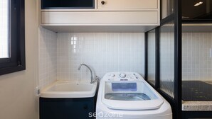 Eine moderne Küche mit integriertem Waschmaschinen, Spüle und Fenster mit Jalousien.
