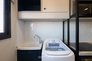 A modern kitchen with a built-in washing machine, a sink, and a window with blinds. - SMT - Building 750m From the Beach in Salvador (Salvador)