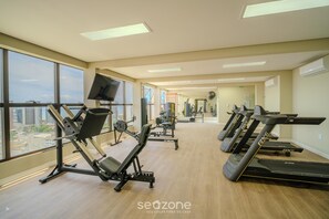 A gym with treadmills, weight machines, and a TV screen. - SMT - Building 750m From the Beach in Salvador (Salvador)