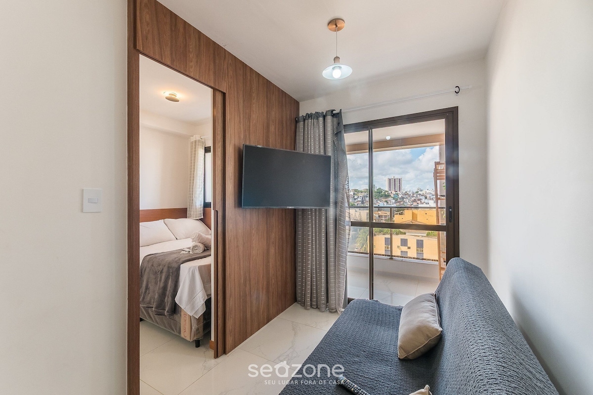 Une chambre moderne équipée d’un lit, d’un canapé, d’une télévision et d’un balcon offrant une vue sur la ville.