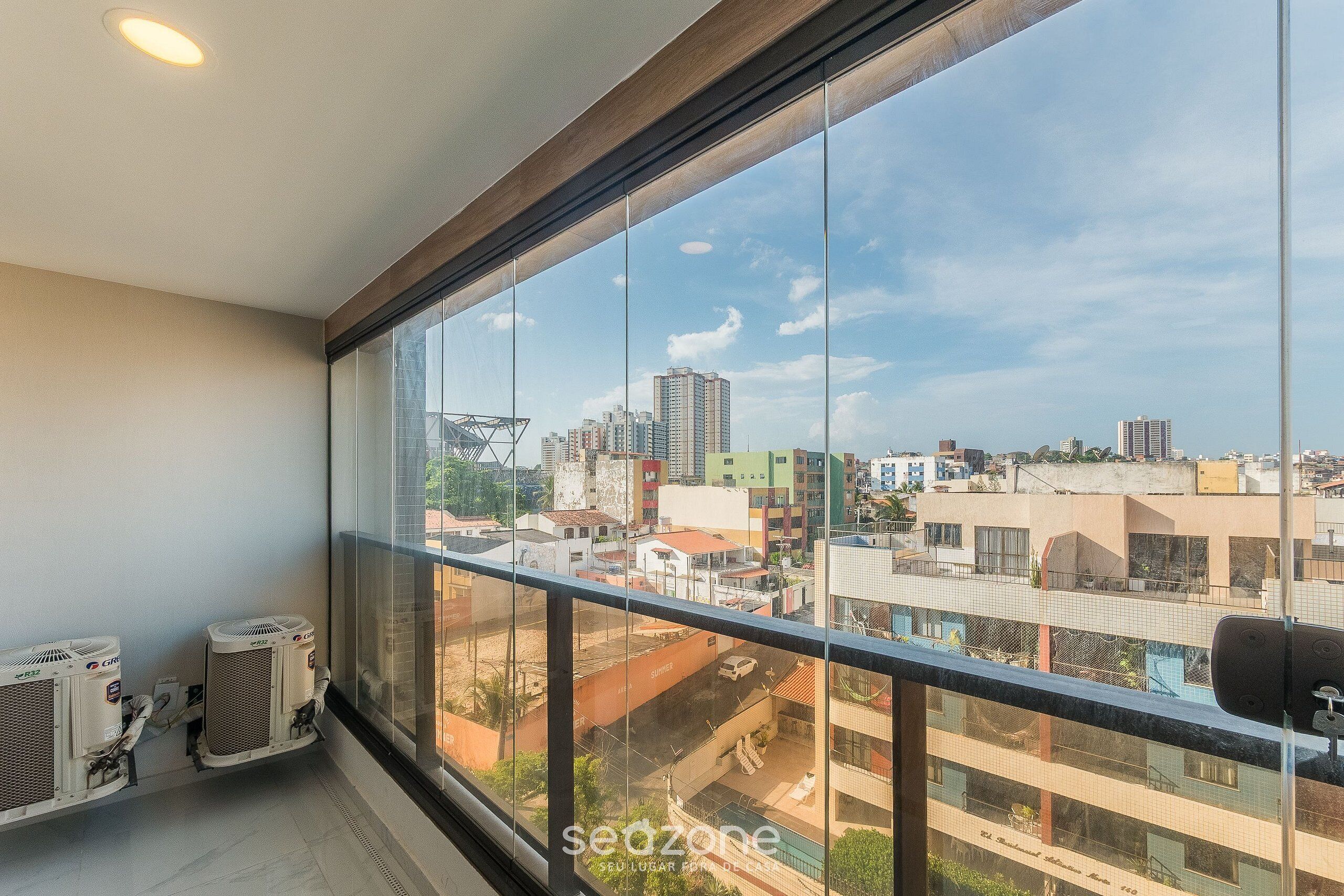 Quarto com amplas janelas, ar condicionado e vista para a paisagem urbana.