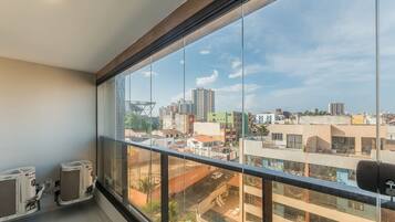 Quarto com amplas janelas, ar condicionado e vista para a paisagem urbana.